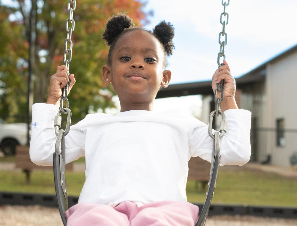 Happy child swinging outdoors at Victory Academy, a Christian daycare and childcare center near downtown Raleigh North Carolina