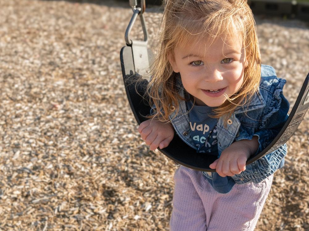 Toddler smiling on a swing at Victory Academy's Raleigh playground