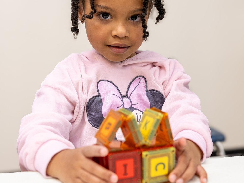 Two-year-old building with letter blocks at Victory Academy preschool in Raleigh