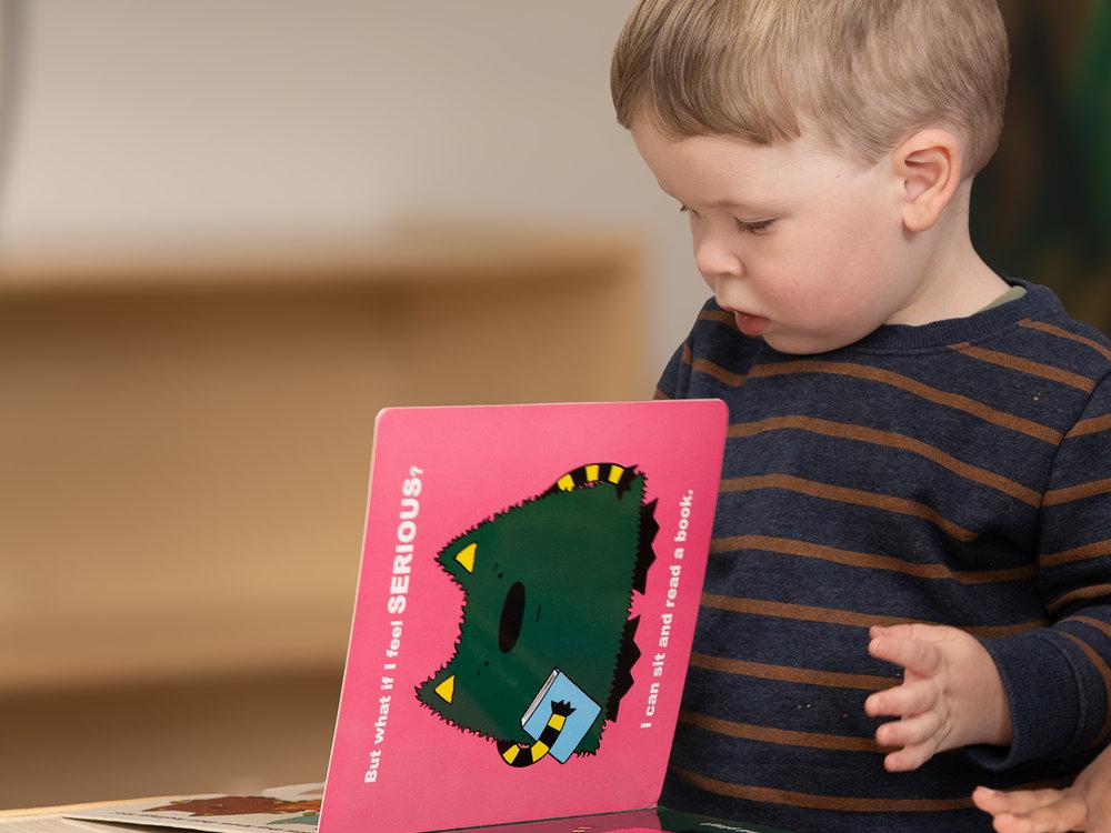 Two-year-old exploring a picture book in the twos preschool classroom at Victory Academy